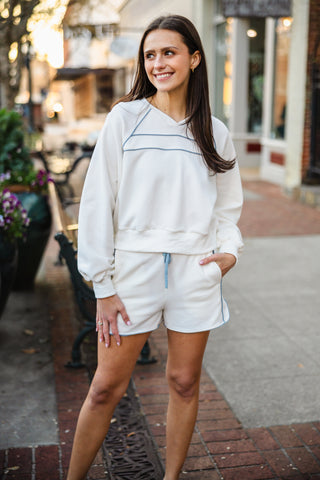 Woman in a white sweatshirt and matching shorts