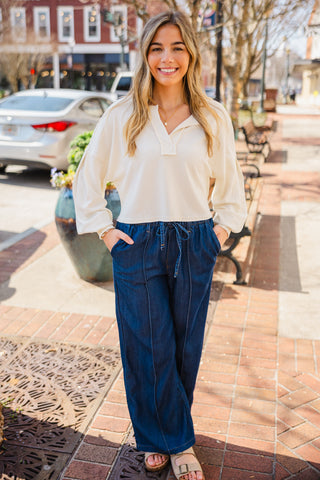 Woman in a off white blouse and blue pants 