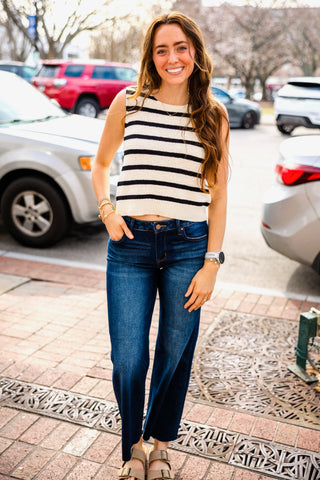Woman wearing a black and off white striped tank top and jeans